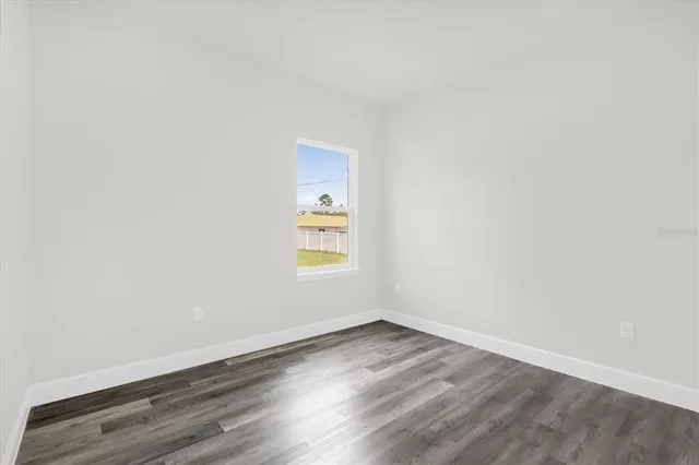 an empty room with wooden floor and window