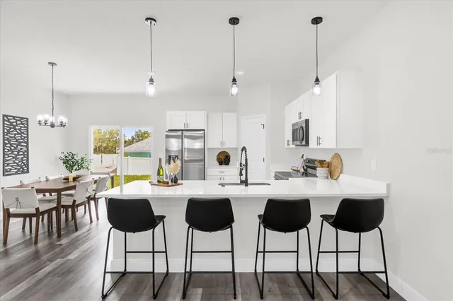 a kitchen with stainless steel appliances a dining table chairs and white cabinets