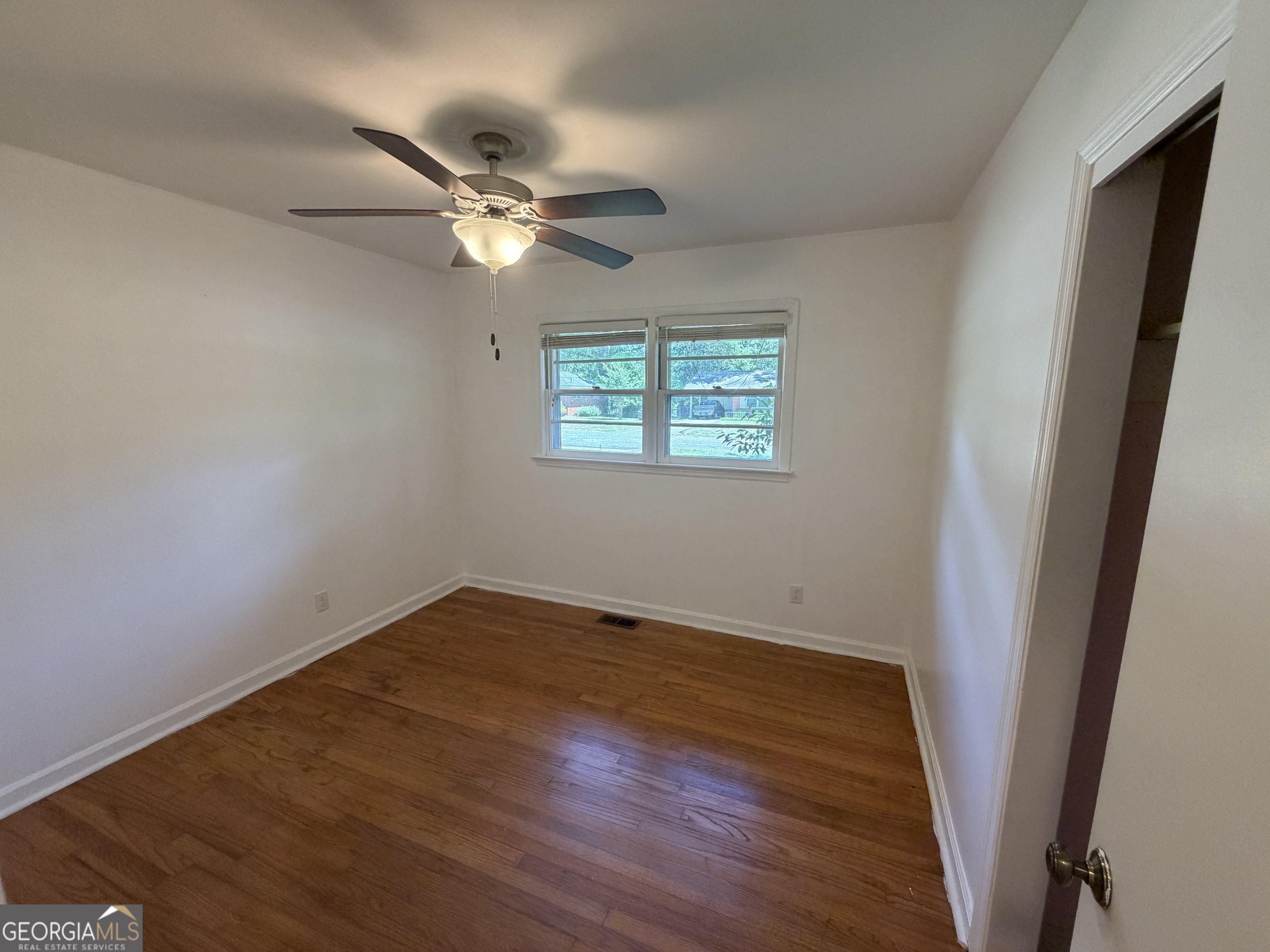 1005 North 1st Street Fort Valley, GA 31030 - Photo 14 of 28 an empty room with wooden floor fan and windows