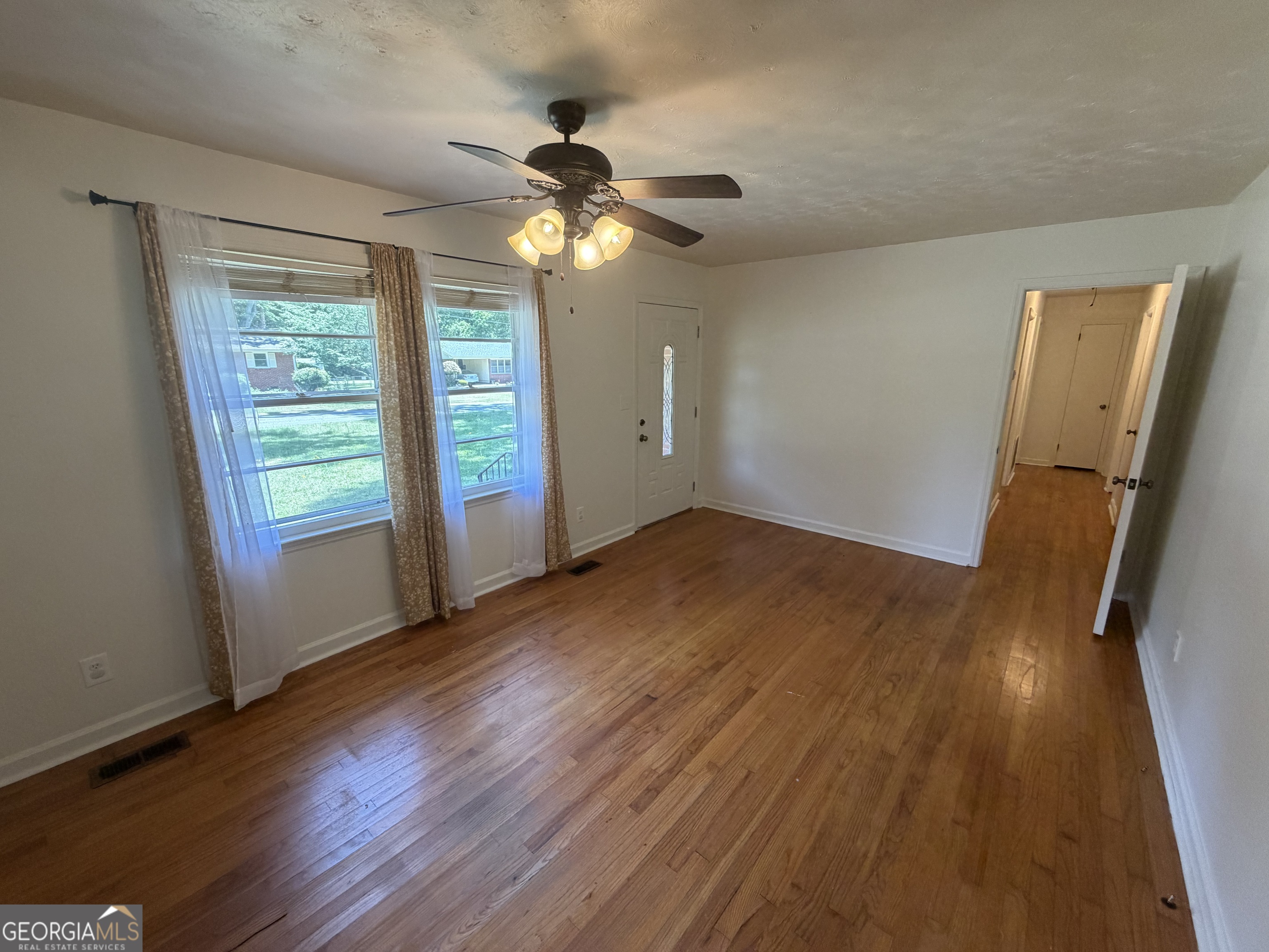 1005 North 1st Street Fort Valley, GA 31030 - Photo 3 of 28 a view of empty room with wooden floor and fan