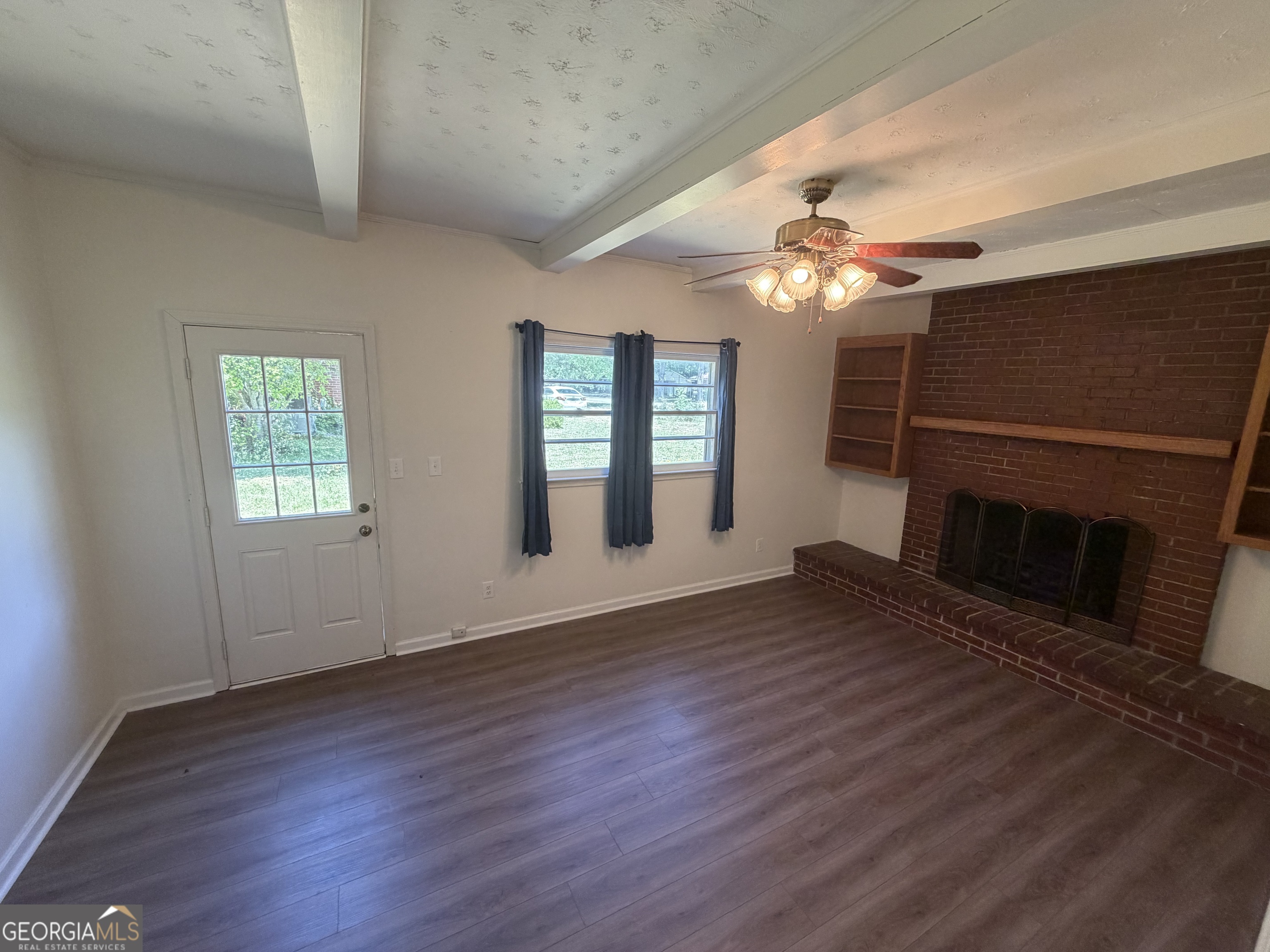 1005 North 1st Street Fort Valley, GA 31030 - Photo 9 of 28 an empty room with wooden floor fireplace and windows