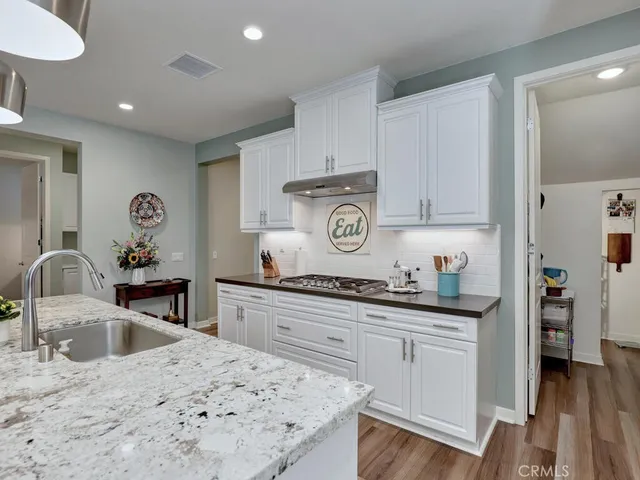 a large kitchen with kitchen island a large island a sink a stove and a large refrigerator with wooden floor