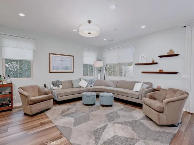 a living room with stainless steel appliances furniture and wooden floor