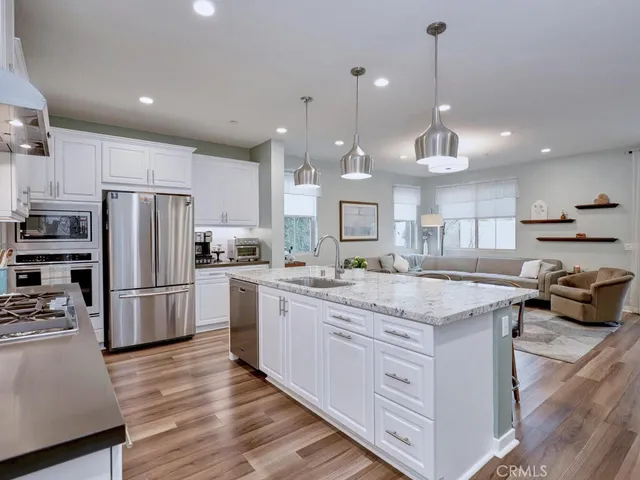 a kitchen with stainless steel appliances kitchen island granite countertop a dining table chairs and white cabinets