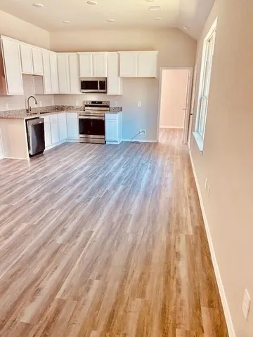 a kitchen with granite countertop a sink dishwasher a stove and a microwave oven with cabinets