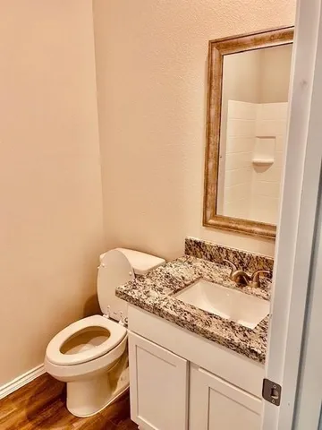 a bathroom with a granite countertop toilet a sink and mirror