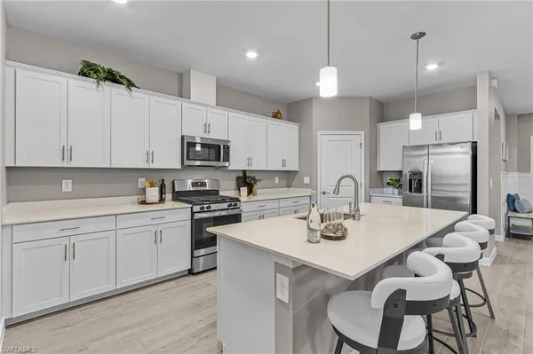 a kitchen with stainless steel appliances granite countertop a sink a stove a refrigerator and white cabinets with wooden floor