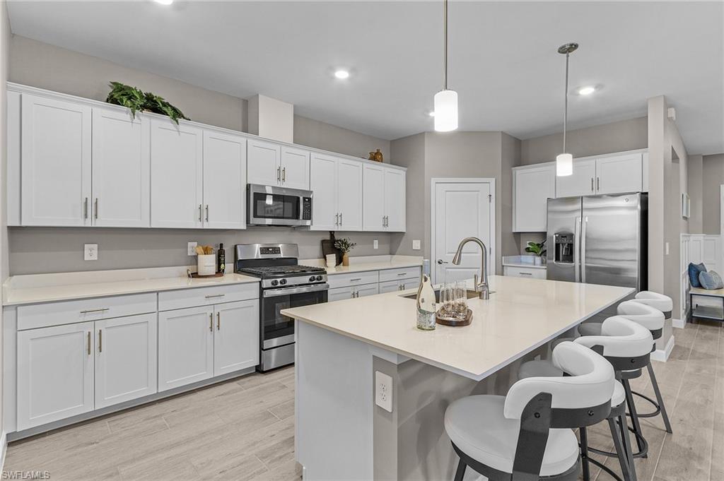 20716 Napa Loop Estero, FL 33928 - Photo 8 of 50 a kitchen with stainless steel appliances granite countertop a sink a stove a refrigerator and white cabinets with wooden floor