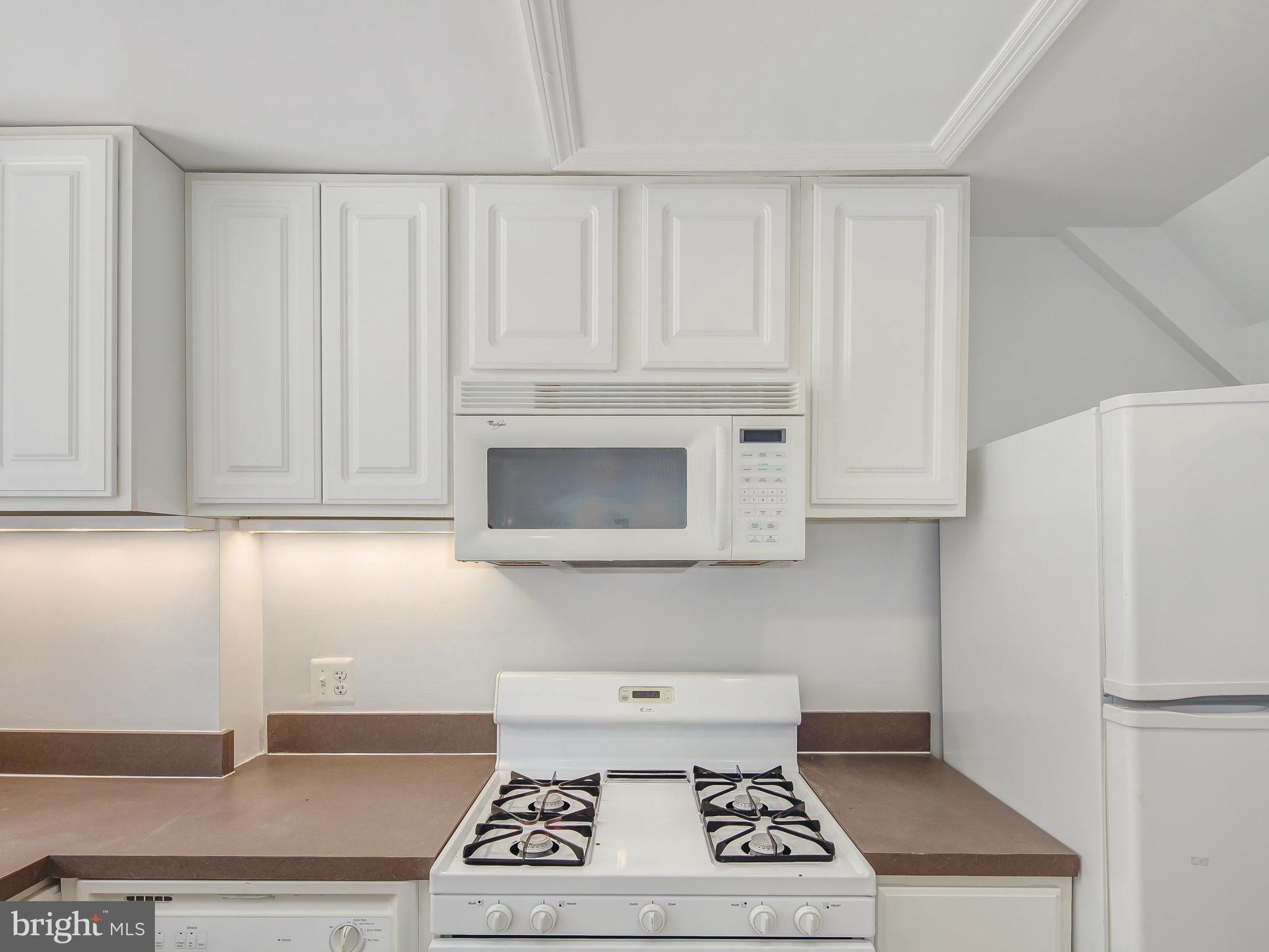 1920 35th Place Northwest Washington, DC 20007 - Photo 15 of 30 a kitchen with granite countertop a stove a microwave and cabinets
