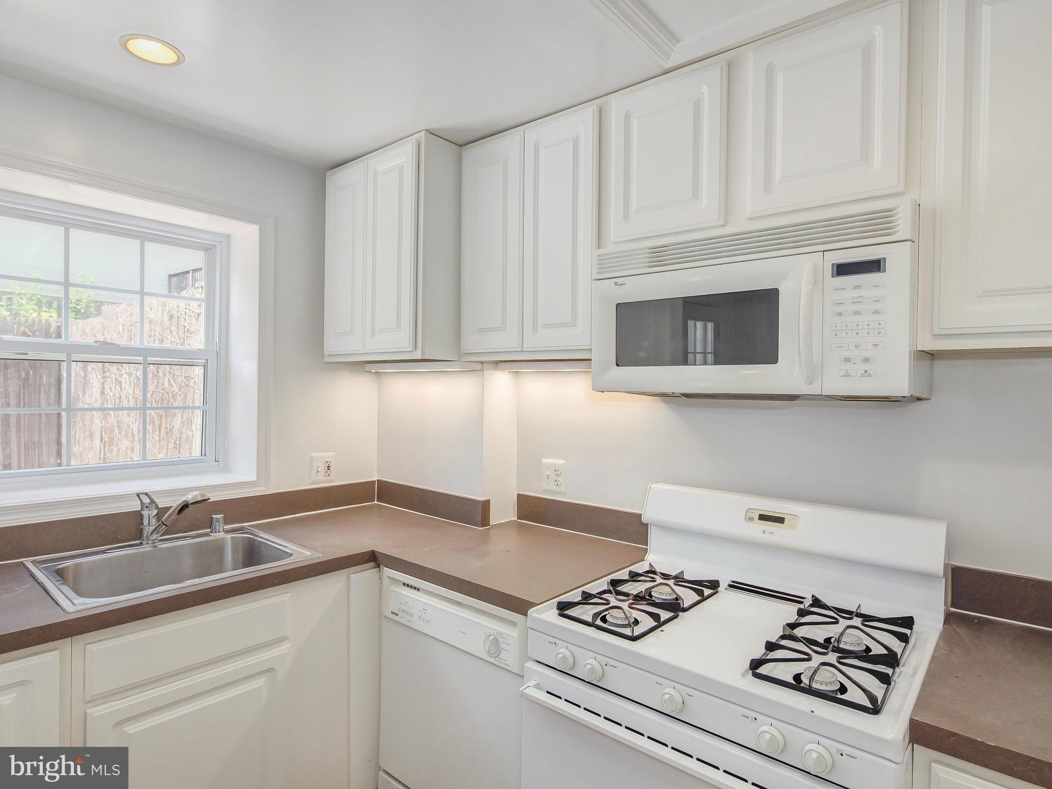 1920 35th Place Northwest Washington, DC 20007 - Photo 16 of 30 a kitchen with granite countertop a stove a sink and a microwave