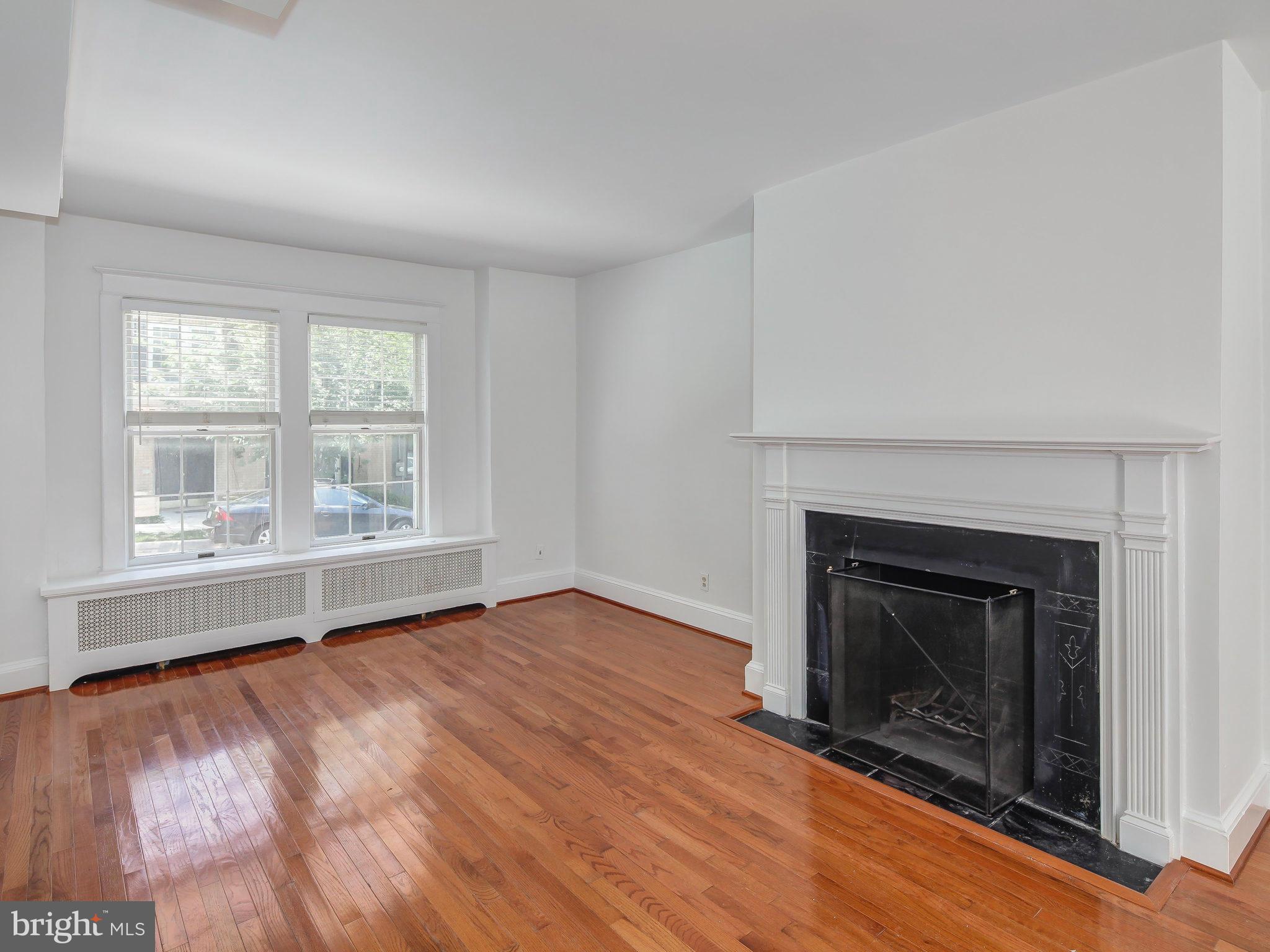 1920 35th Place Northwest Washington, DC 20007 - Photo 7 of 30 an empty room with wooden floor fireplace and windows