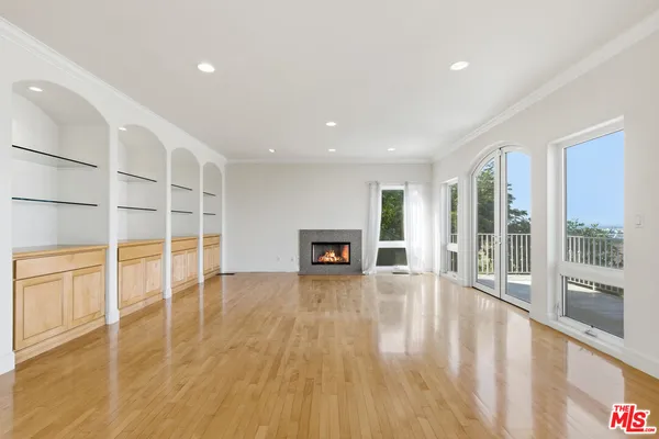 a view of an empty room with glass door and windows
