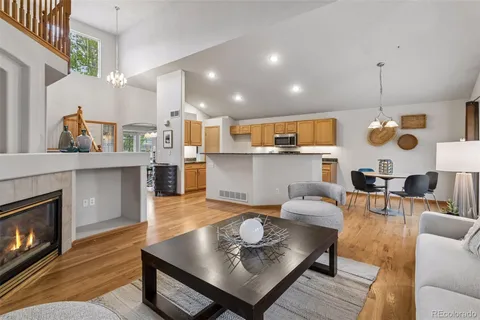a living room with stainless steel appliances furniture a fireplace and a open kitchen view