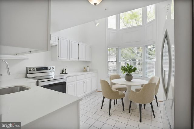 a kitchen with a white cabinets and chairs with a potted plant