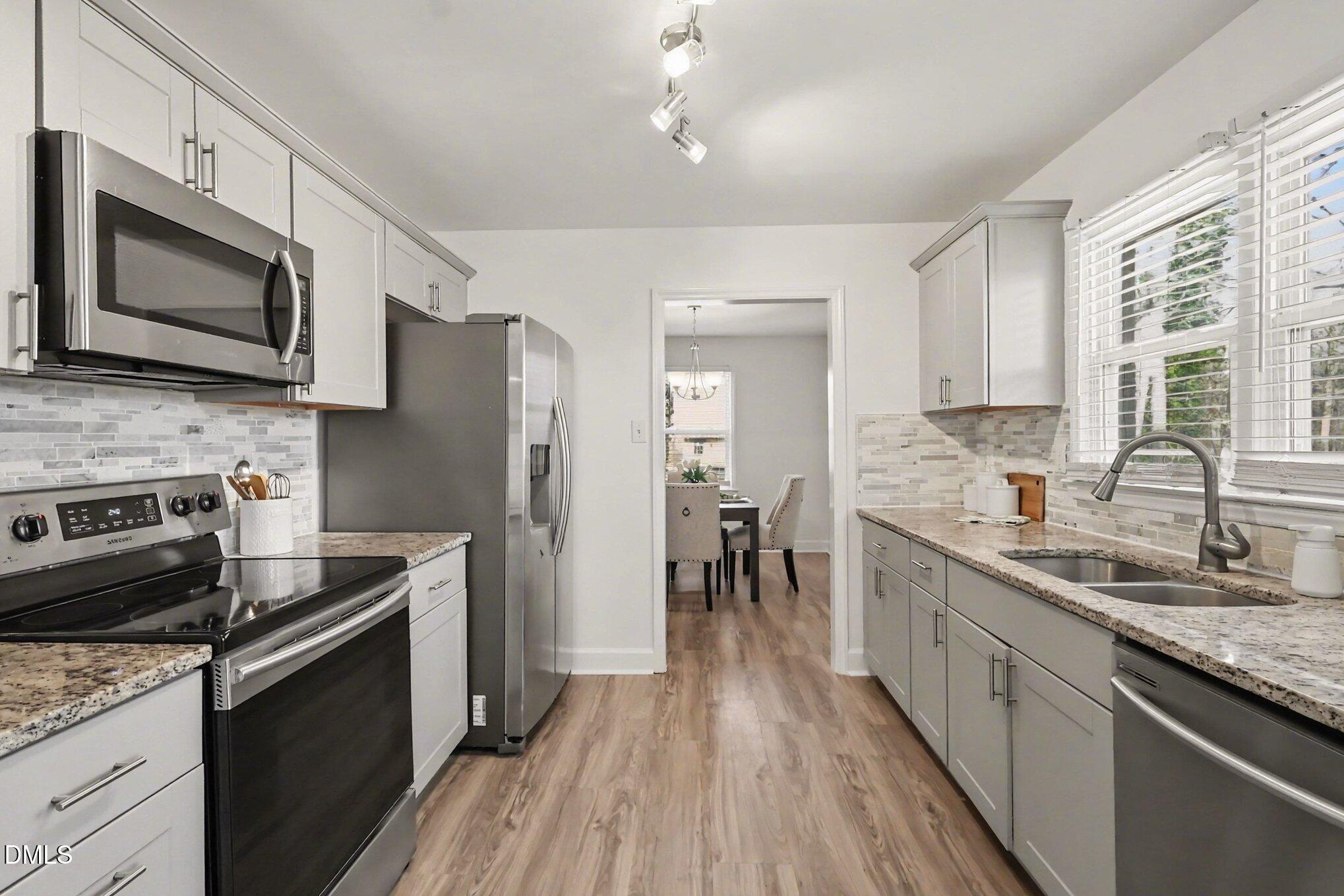 3043 Creech Road Garner, NC 27529 - Photo 11 of 38 a kitchen with stainless steel appliances a stove microwave sink refrigerator and cabinets