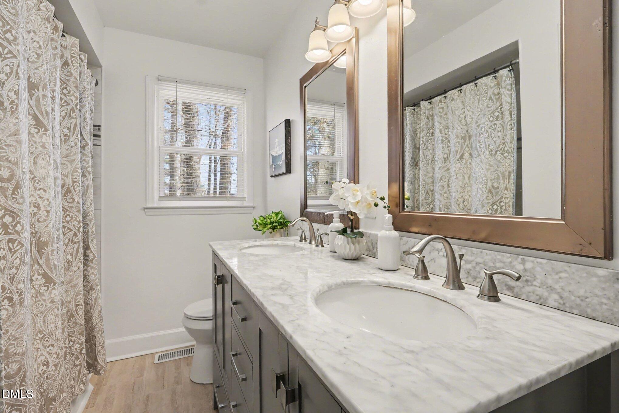 3043 Creech Road Garner, NC 27529 - Photo 20 of 38 a bathroom with a granite countertop sink a toilet and a mirror