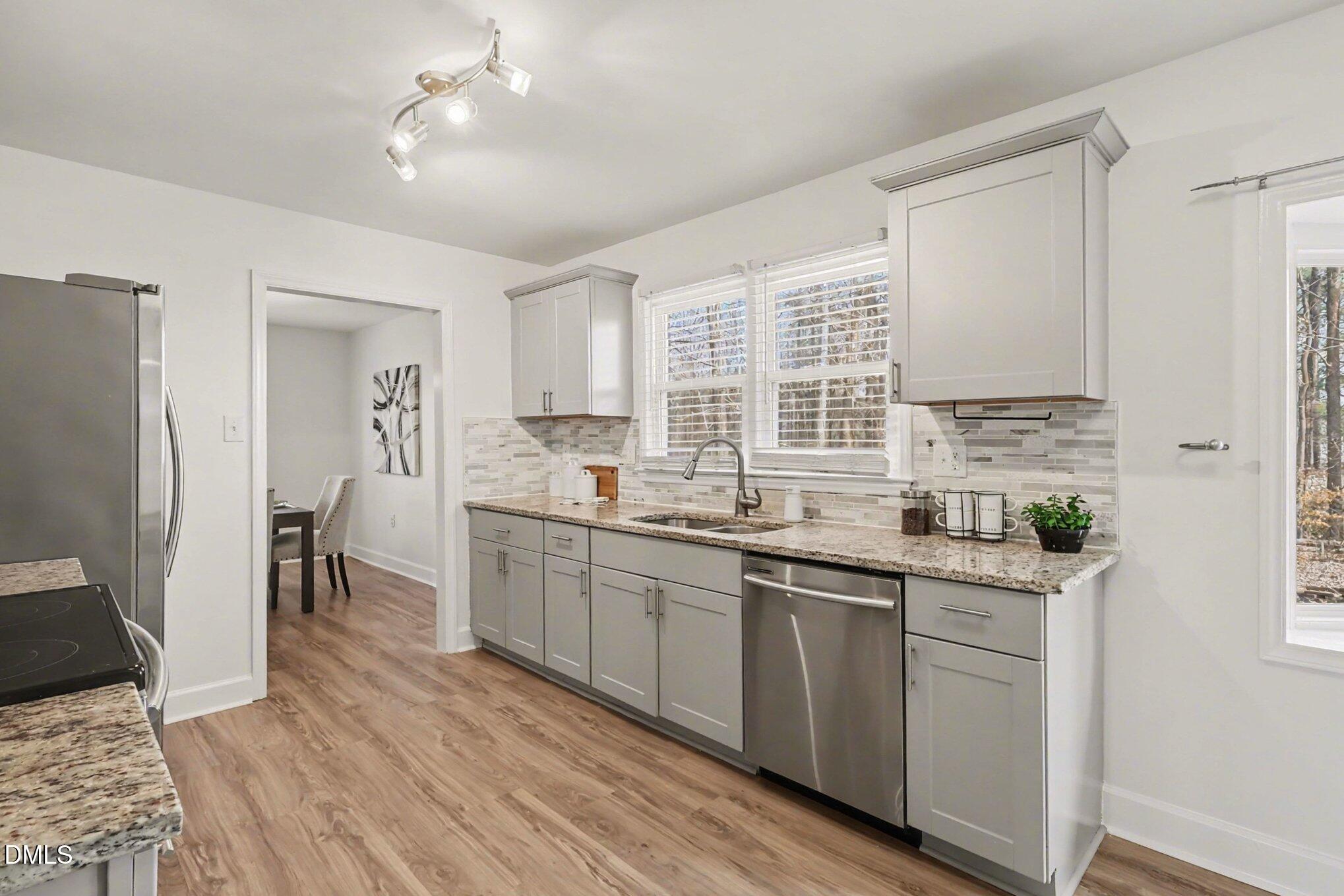 3043 Creech Road Garner, NC 27529 - Photo 8 of 38 a kitchen with stainless steel appliances granite countertop a sink dishwasher a refrigerator and cabinets with wooden floor