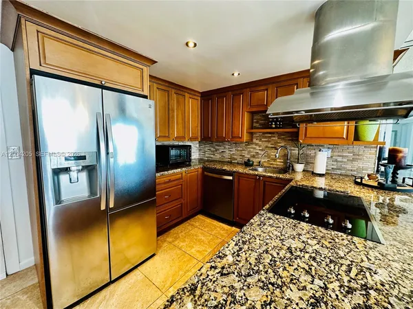 a kitchen with stainless steel appliances granite countertop a refrigerator a sink and a stove