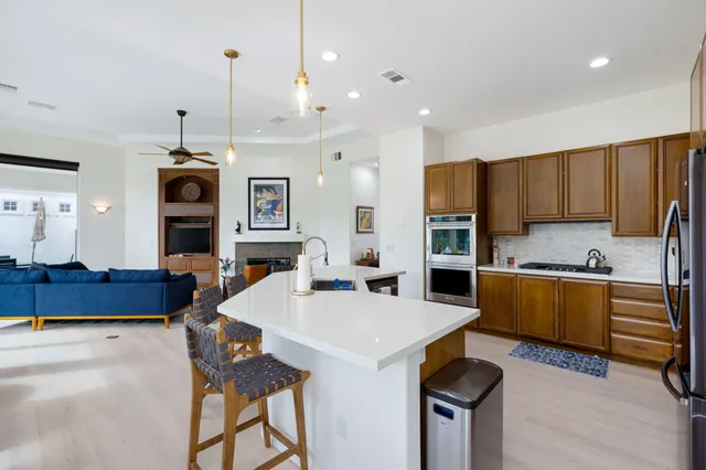 a kitchen with stainless steel appliances a stove sink refrigerator dining table and chairs