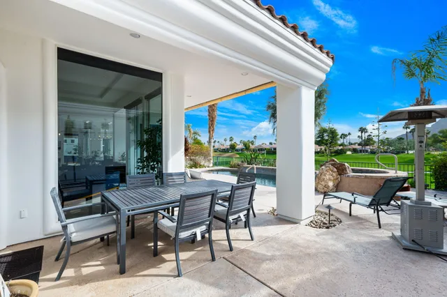 a view of a patio with a dining table and chairs under an umbrella with a fire pit