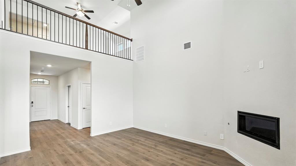 4159 Waldron Trail Forney, TX 75126 - Photo 11 of 19 Living area featuring high ceilings, wood-look flooring, a modern fireplace, and an open loft area with a railing