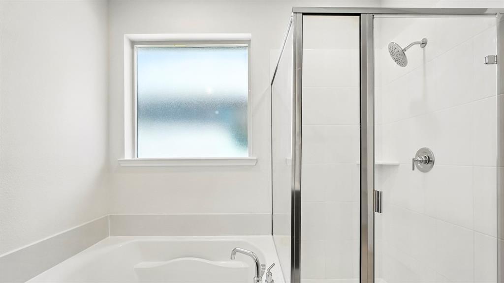 4159 Waldron Trail Forney, TX 75126 - Photo 14 of 19 Bathroom featuring a built-in bathtub, a frosted window, and a shower with a glass enclosure and chrome fixtures