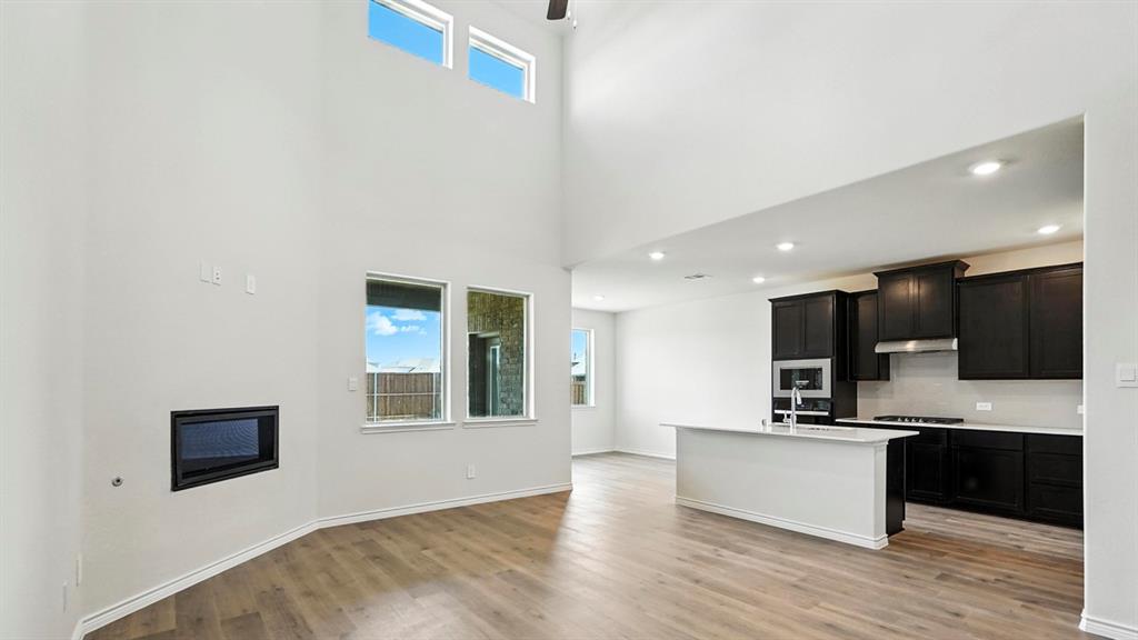 4159 Waldron Trail Forney, TX 75126 - Photo 9 of 19 This open-concept living area features high ceilings, light-colored flooring, and an integrated fireplace