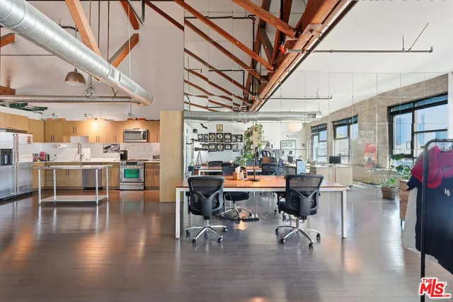 a kitchen with stainless steel appliances kitchen island granite countertop a refrigerator a stove and white cabinets with wooden floor