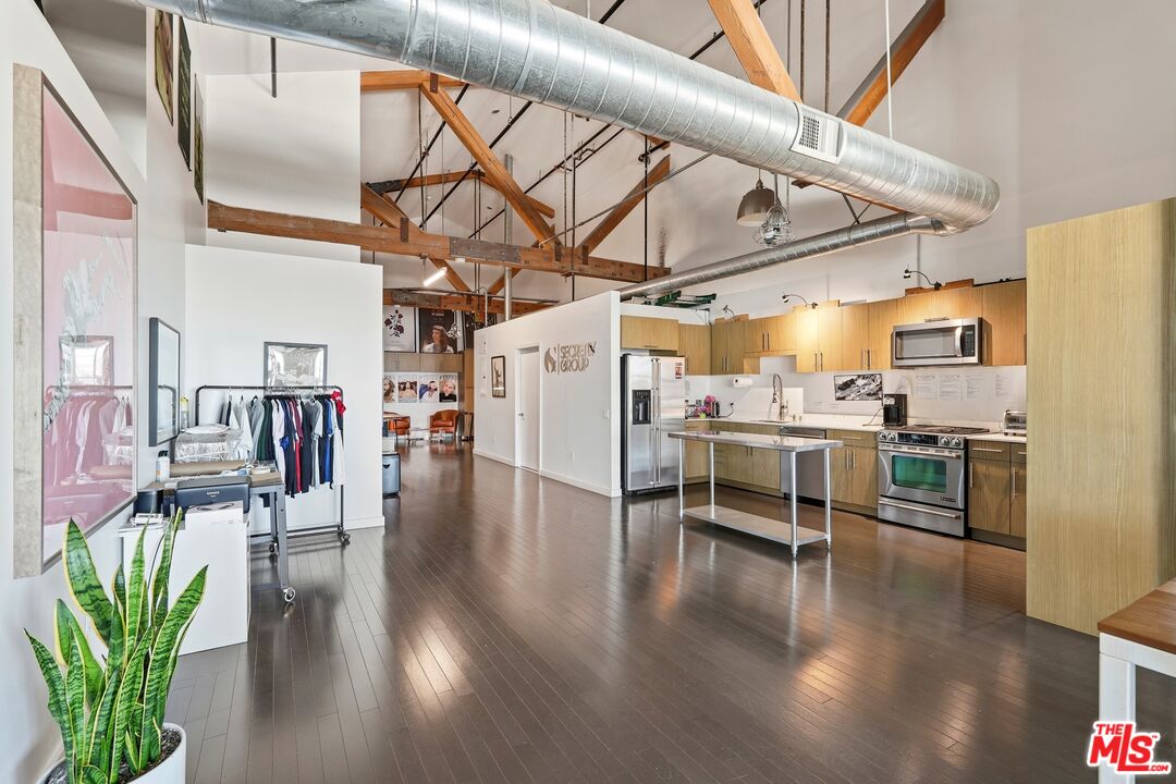 530 South Hewitt Street, Unit 533 Los Angeles, CA 90013 - Photo 17 of 57 a kitchen with stainless steel appliances kitchen island granite countertop a refrigerator a stove and white cabinets with wooden floor