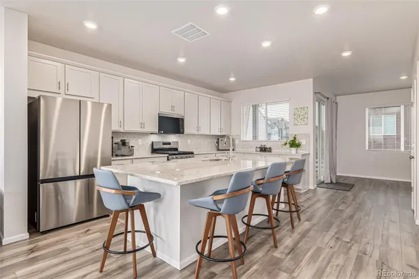 a kitchen with stainless steel appliances a refrigerator a stove a sink dishwasher and a refrigerator with wooden floor