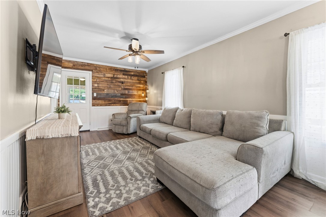 258 Randolph Road Mogadore, OH 44260 - Photo 9 of 49 Living area featuring wood-finish flooring, a rustic wood accent wall, white wainscoting, and a ceiling fan with integrated lighting