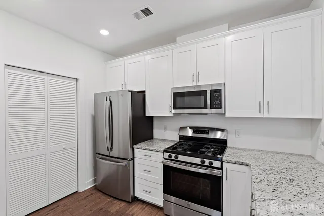 a kitchen with granite countertop a sink stainless steel appliances and cabinets
