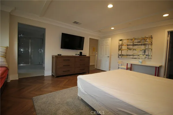a spacious bedroom with a bed and a flat screen tv
