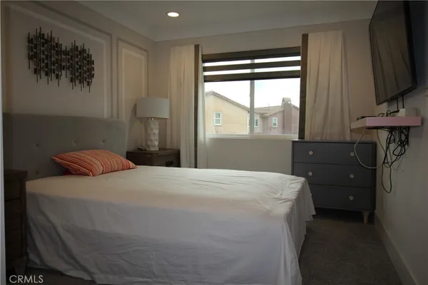 a bedroom with a bed and a flat tv screen on the dresser