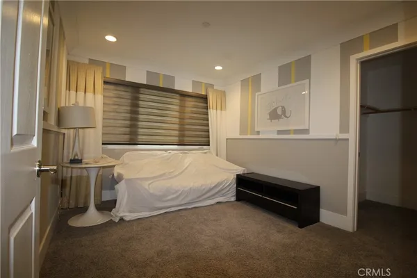 a bedroom with a bed and a refrigerator