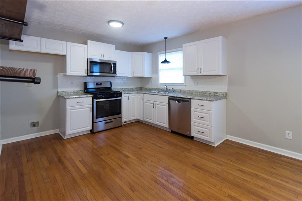 374 McGiboney Road Covington, GA 30016 - Photo 8 of 29 a kitchen with stainless steel appliances granite countertop a stove top oven a sink dishwasher and a microwave oven on the wooden floor