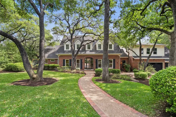 a front view of a house with a garden and trees
