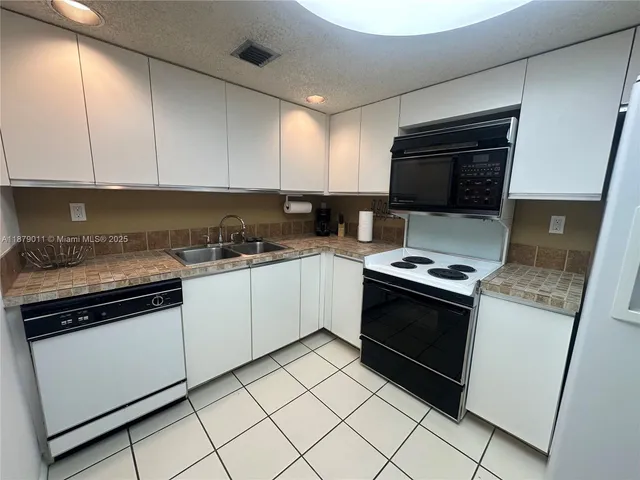 a kitchen with a refrigerator sink and cabinets