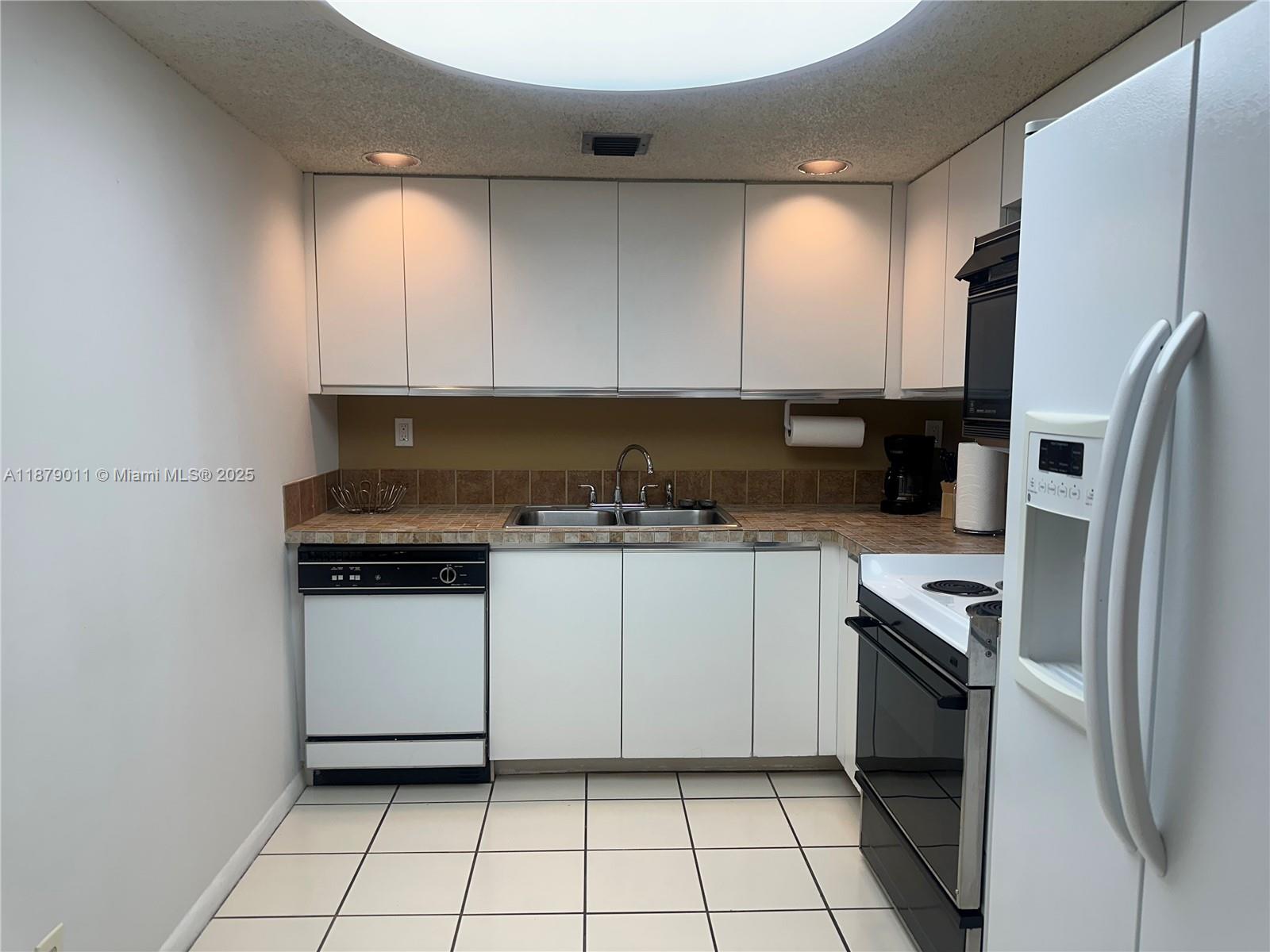 5415 Collins Avenue, Unit 302A Miami Beach, FL 33140 - Photo 7 of 20 a kitchen with a refrigerator sink and cabinets