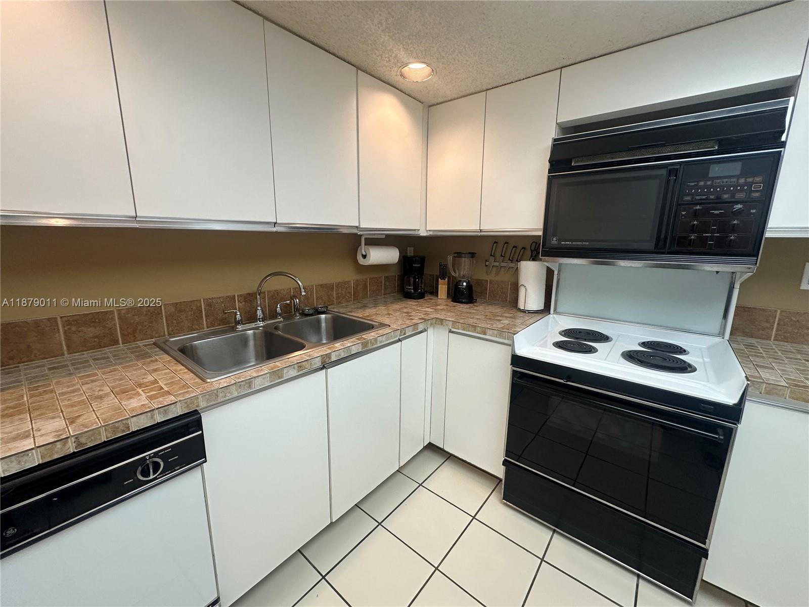 5415 Collins Avenue, Unit 302A Miami Beach, FL 33140 - Photo 8 of 20 a kitchen with granite countertop a sink stove and cabinets