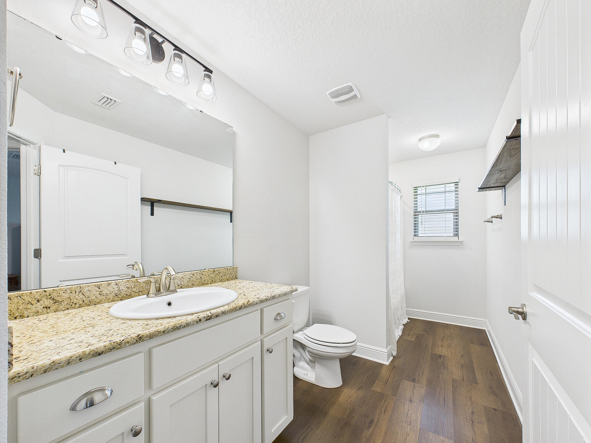 5740 Marigold Loop Crestview, FL 32539 - Photo 20 of 47 a bathroom with a granite countertop sink a toilet and a large mirror