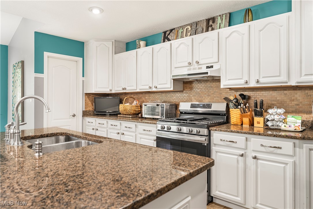155 Ridgewood Boulevard Belpre, OH 45714 - Photo 25 of 49 Kitchen with decorative backsplash, white cabinetry, dark stone counters, and under cabinet range hood