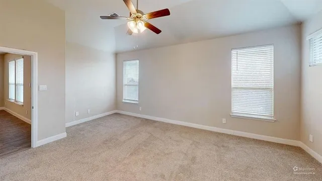 an empty room with windows and fan