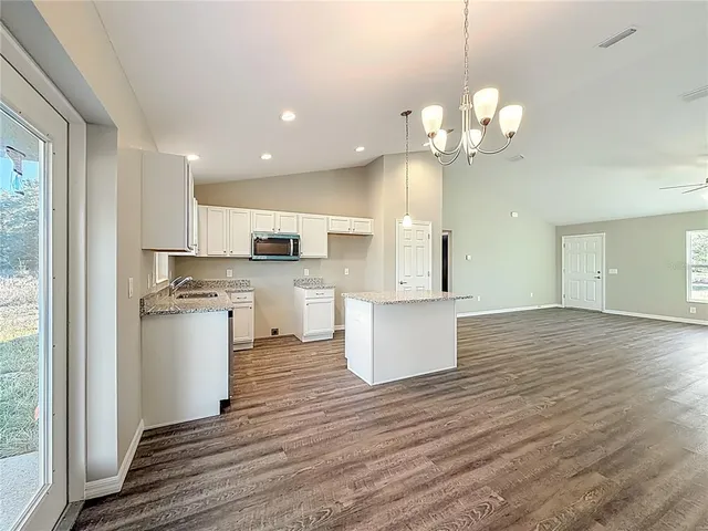 a large kitchen with kitchen island a stove a sink a center island and wooden floor