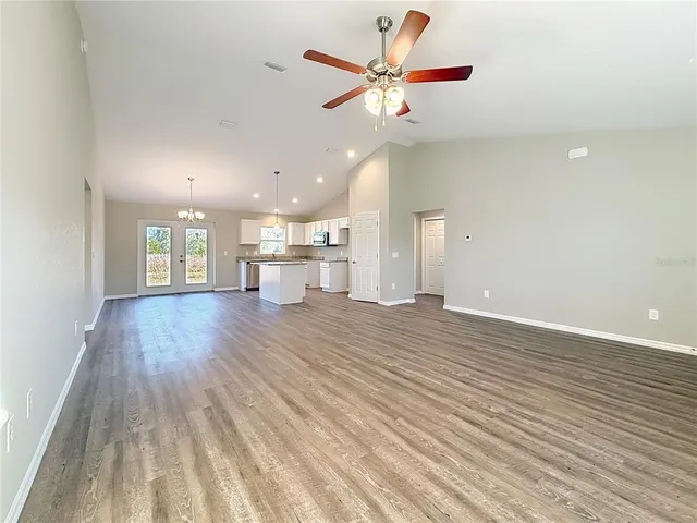 a view of an empty room with wooden floor and a ceiling fan