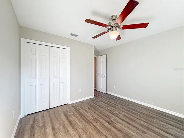 an empty room with wooden floor fan and windows