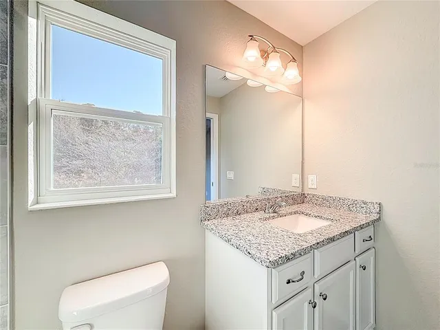 a bathroom with a granite countertop sink a toilet and a mirror