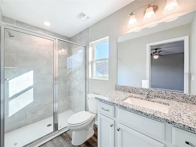 a bathroom with a granite countertop sink toilet and shower