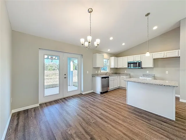 a large kitchen with hardwood floor a sink stainless steel appliances and cabinets