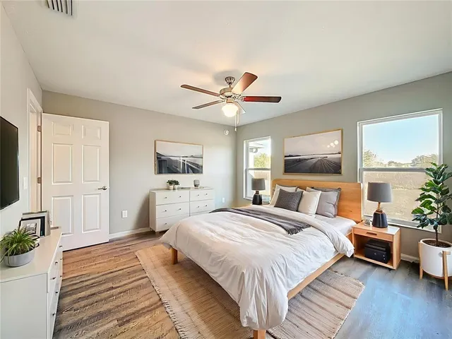 a bedroom with a large bed a flat tv screen and a potted plant